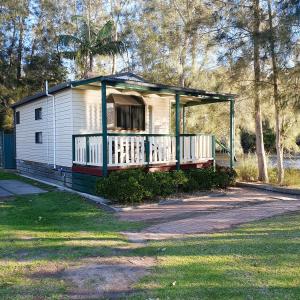 una piccola casa bianca con un portico in cortile di Pleasurelea Tourist Resort & Caravan Park a Batemans Bay