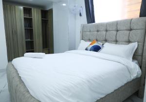 a large bed with white sheets and pillows at Casa-Koker Residences in Kisumu