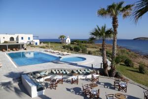 a swimming pool with chairs and a view of the ocean at Poseidon of Paros Hotel & Spa in Chrissi Akti