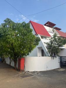 a white house with a red roof and a white fence at Lotus in Lonavala
