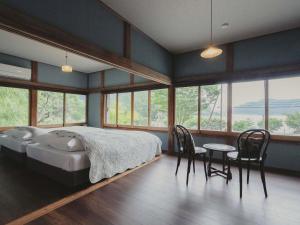 Un dormitorio con una cama y una mesa y sillas. en THE LAKE Kawaguchiko-kurashi, en Fujikawaguchiko