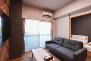 福岡市にあるHotel ROI 博多のソファとベッドのあるリビングルーム