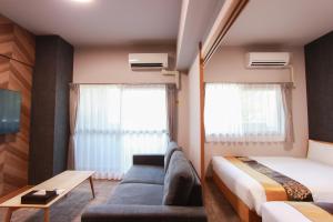 a hotel room with a couch and a bed at Hotel ROI 博多 in Fukuoka