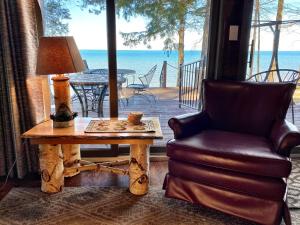 a living room with a chair and a table with a lamp at Lakefront Pine Cottage Hot Tub & Fire Pit in Sodus