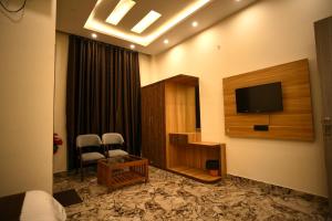 a hotel room with a television and two chairs at Hotel JB Square Ayodhya Near Ram Mandir, Airport & Ayodhya Cantt in Ayodhya