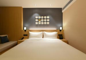 una camera da letto con un grande letto bianco e un divano di Beijing Guomao Business District Sihui Orange Crystal Hotel a Pechino