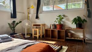 Un dormitorio con una cama y algunas plantas y una ventana. en Baan PadSeeEw - Rooftop Riverview 2nd floor, en Thonhuri