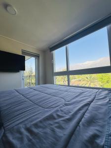 ein Schlafzimmer mit einem großen Bett mit einem großen Fenster in der Unterkunft Departamento vista cordillera alto la florida in Santiago