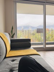 eine Person, die vor einem Fenster auf einer Couch liegt in der Unterkunft Departamento vista cordillera alto la florida in Santiago