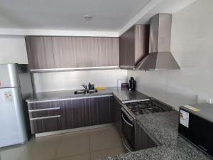 een keuken met bruine kasten en een kookplaat oven bij AC Suites XL in Puerto Madryn