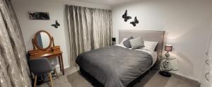 a bedroom with a bed and a mirror and a chair at Dewdrop Cottage in Hastings