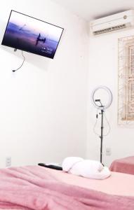 a tv hanging on a wall above a bed at Casa no Jardim Renascença- Bird House Renascença in São Luís