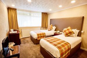 a hotel room with two beds and a television at Abbotsford Hotel in Dumbarton