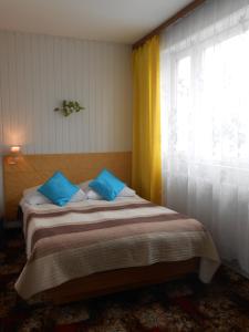 a bedroom with a bed with blue pillows and a window at Hotel Leon in Biała Podlaska