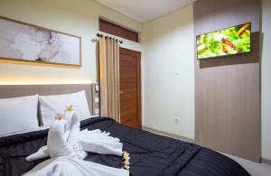 a bedroom with a bed with a tv on the wall at Opang Asri Guesthouse Sanur in Sanur