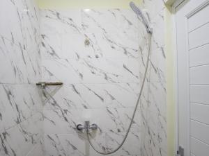 a bathroom with a shower with white marble walls at Opang Asri Guesthouse Sanur in Sanur
