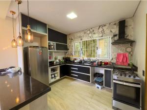 a large kitchen with a stainless steel refrigerator at Casa Aconchegante na Serra da Cantareira em Condomínio Fechado in Mairiporã