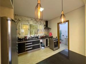 a kitchen with two pendant lights and a kitchen with a refrigerator at Casa Aconchegante na Serra da Cantareira em Condomínio Fechado in Mairiporã +7 photos