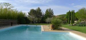 a swimming pool in a yard with trees and a field at Chambres d'hôtes du Domaine de la Manse in Villeneuve-de-Berg