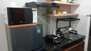 a small kitchen with a microwave and a sink at FREE WIFI, NETFLIX, SMART TV, MINERAL WATER, AMENITIES - Studio with Foldable Wall Bed at Serpong Garden Apt in Cisauk 1