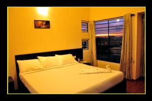a bedroom with a large white bed with a window at The Hill Side in Ooty
