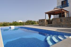 a swimming pool with chairs and a gazebo at Ariadne House in Agia Anna Naxos