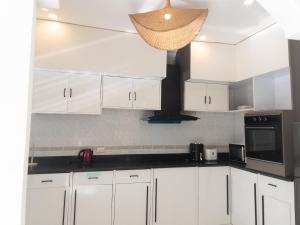 een witte keuken met witte kasten en een magnetron bij Paradise House in Thai Muang