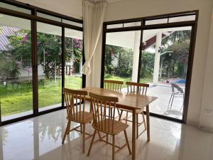 a wooden table and chairs in a room with windows at Paradise House in Thai Muang