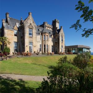 un vieux château avec une pelouse devant lui dans l'établissement Stonefield Castle Hotel ‘A Bespoke Hotel’, à Stonefield