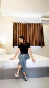 a woman sitting on top of a bed at Wisma Lotus 2 Purwokerto in Banyumas