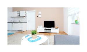 a white living room with a tv and a table at Apartment Saraj-Bosna Free public Parking in Sarajevo