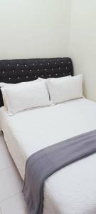 a white bed with a black headboard and white pillows at Bumiemas Homestay - 2 BEDROOM in Kangar
