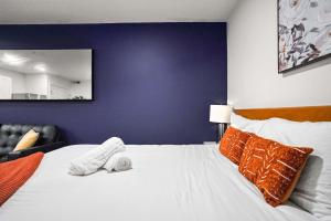 a bedroom with a large white bed with orange pillows at CozySuites Stunning 1BR in Downtown Pitts #1 in Pittsburgh