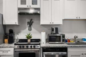 a kitchen with white cabinets and a stove and a microwave at CozySuites Stunning 1BR in Downtown Pitts #1 in Pittsburgh +4 photos