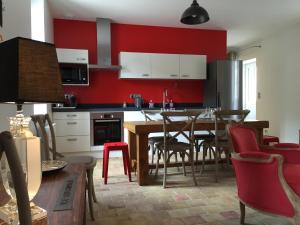 a kitchen with red walls and a table and chairs at La Maison des Belles Filles in Pernand-Vergelesses