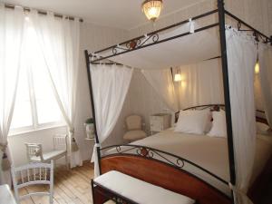 a bedroom with a canopy bed and a chair at Hôtel De La Providence in Égliseneuve-dʼEntraigues