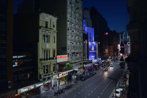una concurrida calle de noche con coches y edificios en Tango Bs As Multipremiado! Cuidamos su estadía en Buenos Aires