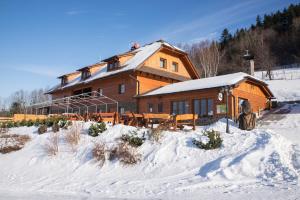 een groot houten huis met sneeuw op de grond bij Penzion U Pacošů in Malenovice