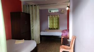 een kleine kamer met 2 bedden en een stoel bij Sweet Home Guest House in Shillong
