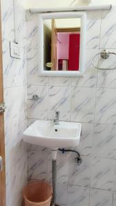 een witte badkamer met een wastafel en een spiegel bij Sweet Home Guest House in Shillong