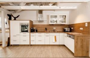 een keuken met witte kasten en houten vloeren bij Ferienwohnung Stempfle in Oberstdorf