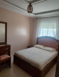 a bedroom with a bed with a blue headboard and a television at Dyar alboughaz in Hajreien