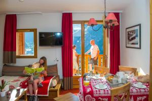 una mujer y un niño leyendo un libro en una sala de estar en Résidence Goélia Les Chalets Valoria, en Valloire