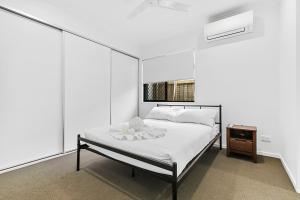 a white bedroom with a bed and a night stand at Charlotte's Place in Caboolture