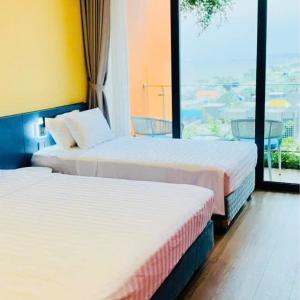 two beds in a hotel room with a large window at Thành phố Flamingo Hải Tiến City Ibiza Resort Biển 5 Sao KS 21 tang -SeaNest 609 in Thanh Hóa