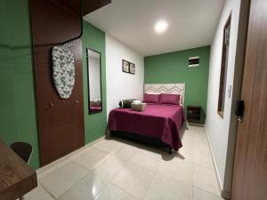 a bedroom with a pink bed and green walls at Olivo House in Envigado