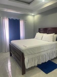 迪斯卡弗里贝Blue coral Villa Jamaica的卧室里有一张大床，床单和枕头都是白色的