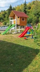 a playground with slides and a house in the background at Apartments Stari Jasen Uvac in Sjenica
