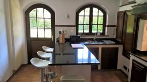 a kitchen with a black counter and white chairs at Villa Sous-Bois Marie in Spa