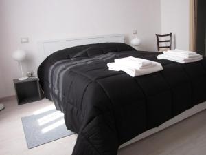 un letto nero con asciugamani bianchi sopra di Susasei a Torino
